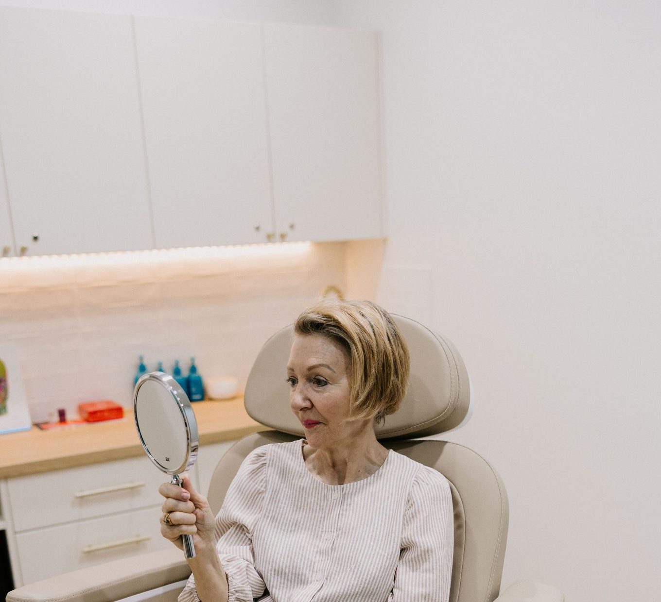 A patient holding a mirror while the chin and jawline are assessed.