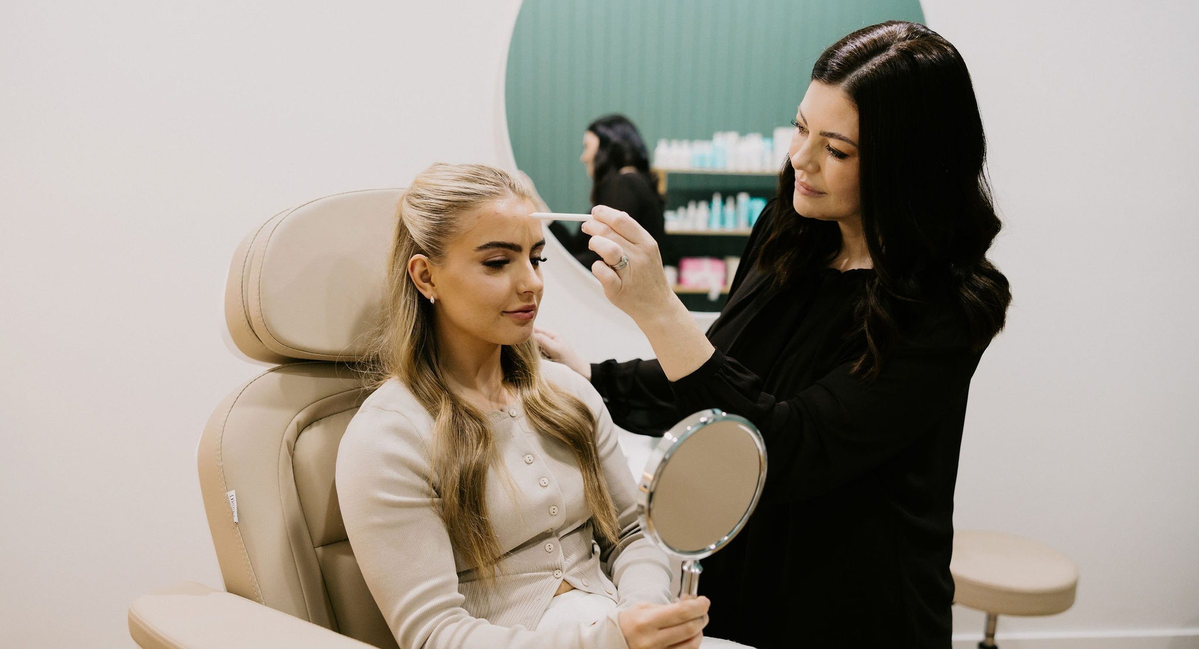 Sarah Munnings assessing a patient’s brow while the patient holds a mirror.