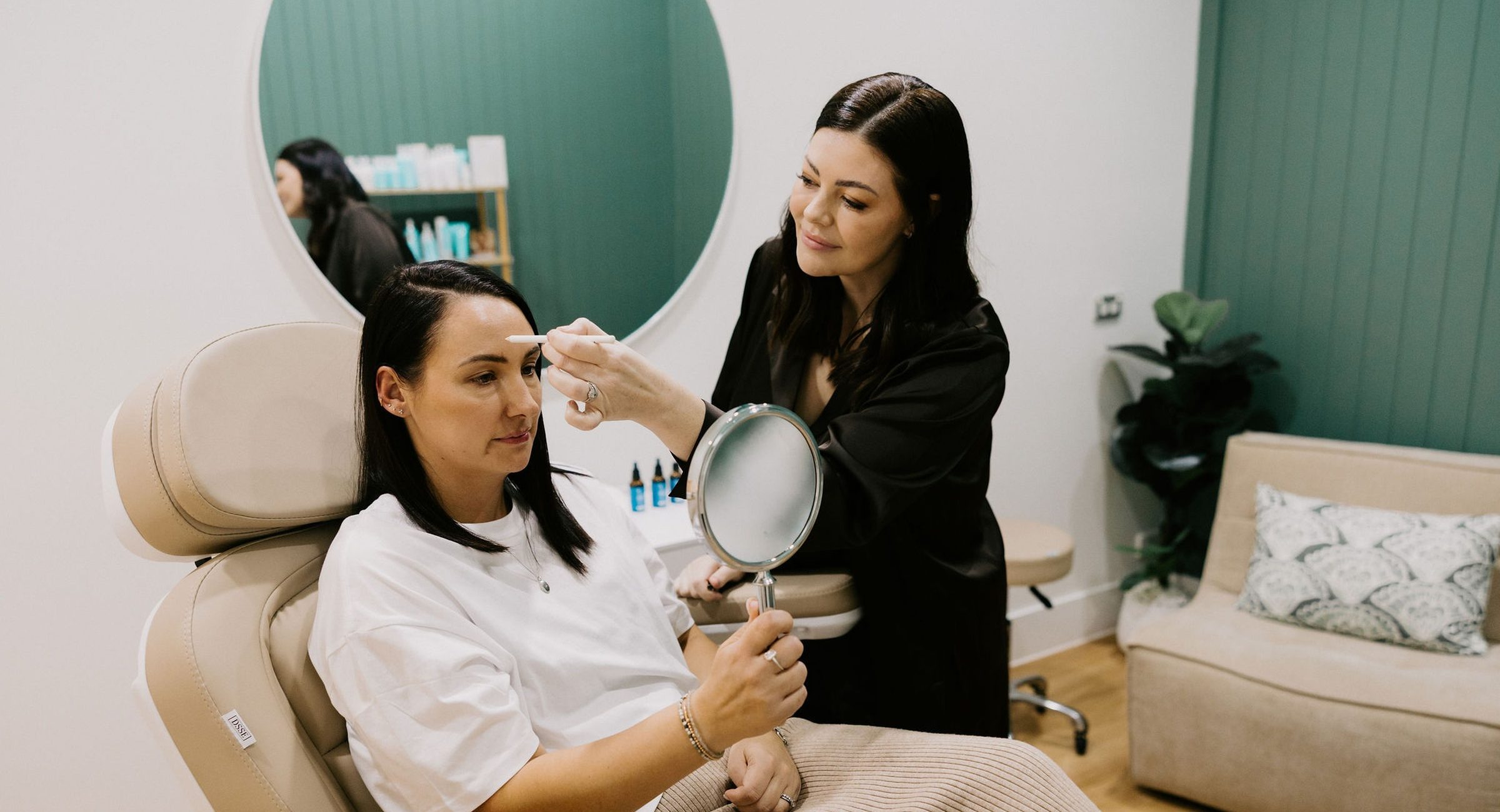 Sarah Munnings assessing a patient’s midface, the patient holding a mirror.